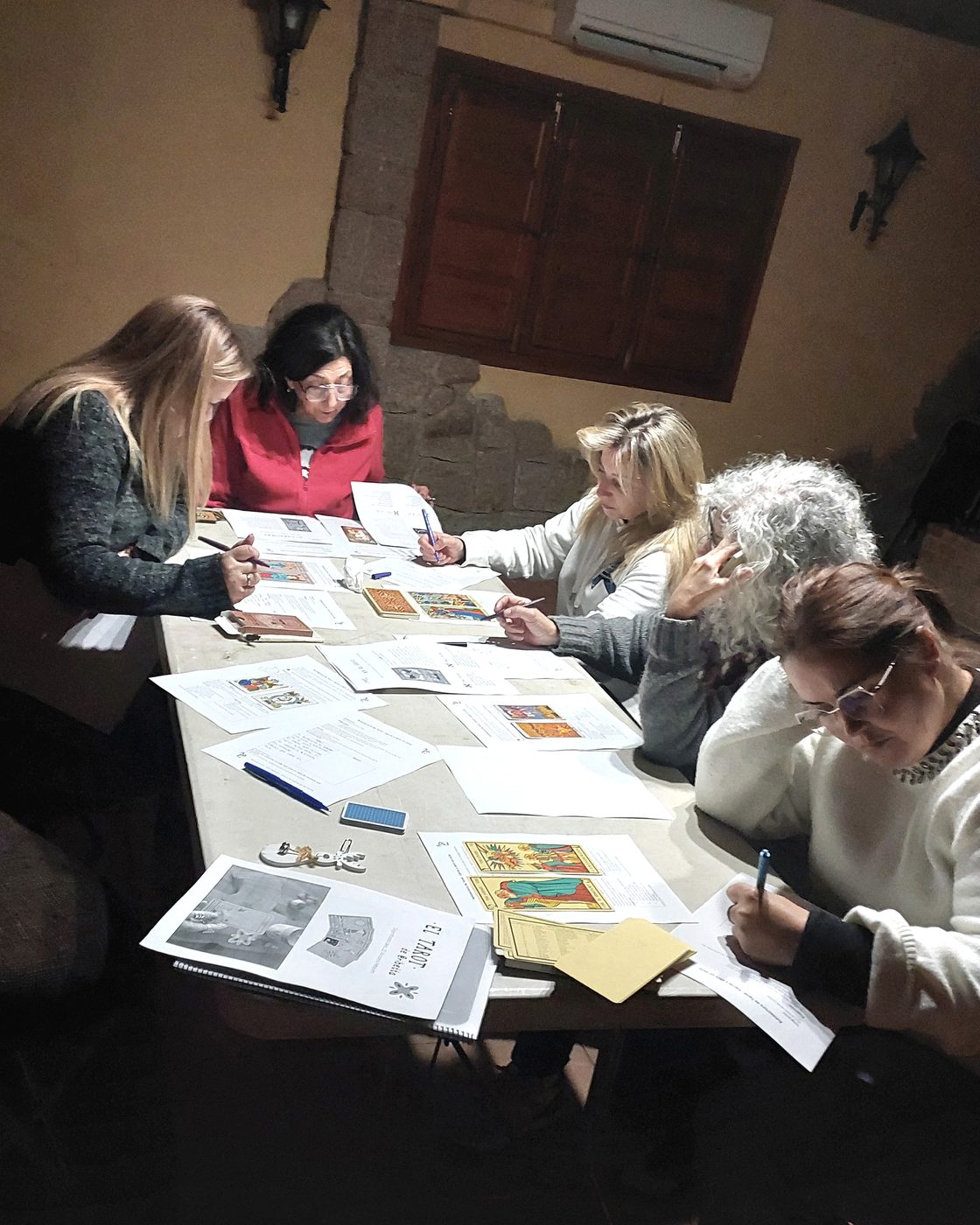 Mujeres compartiendo un taller de Tarot en un espacio interior acogedor.