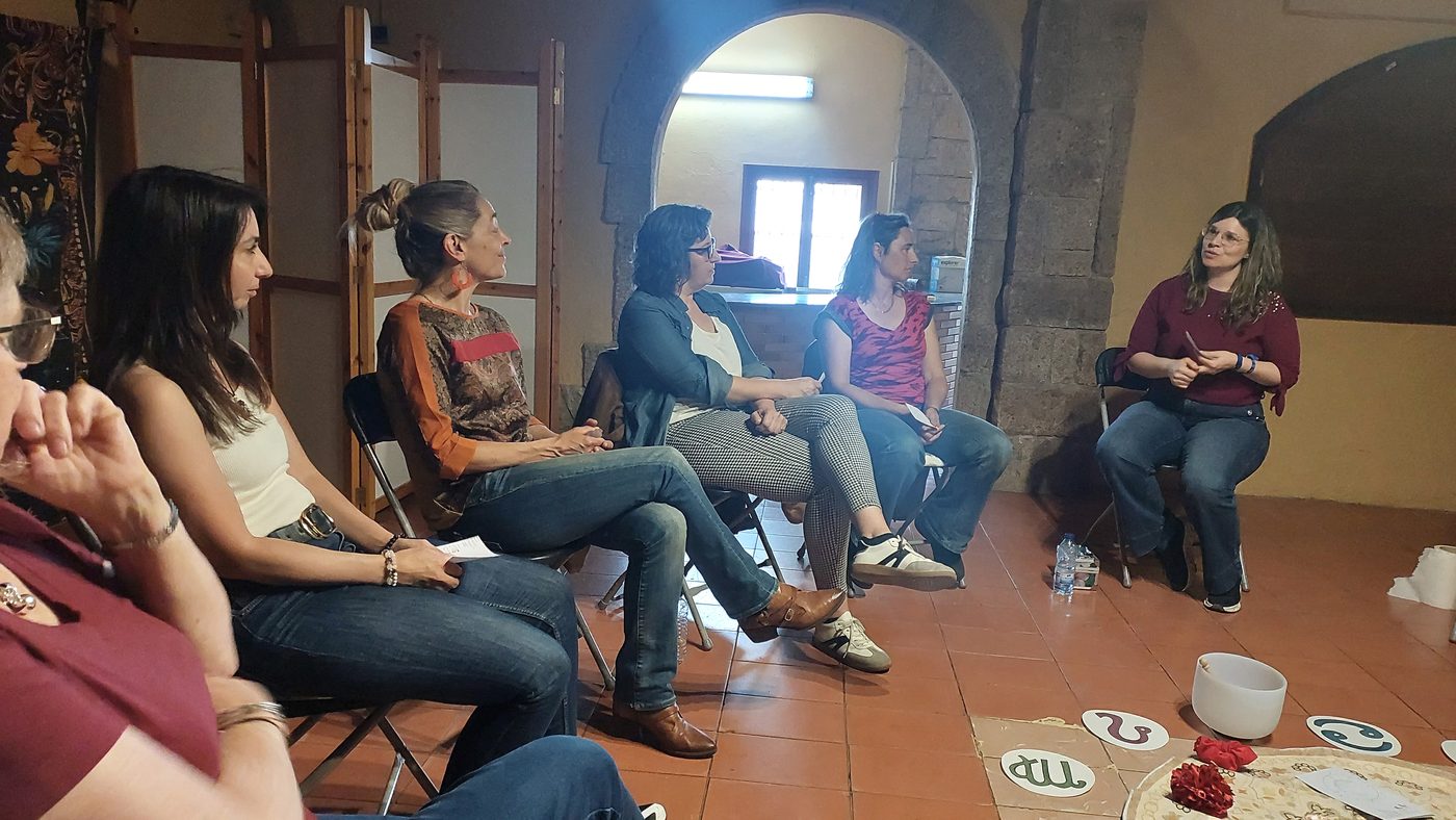 Mujeres conversando en círculo en un espacio interior.