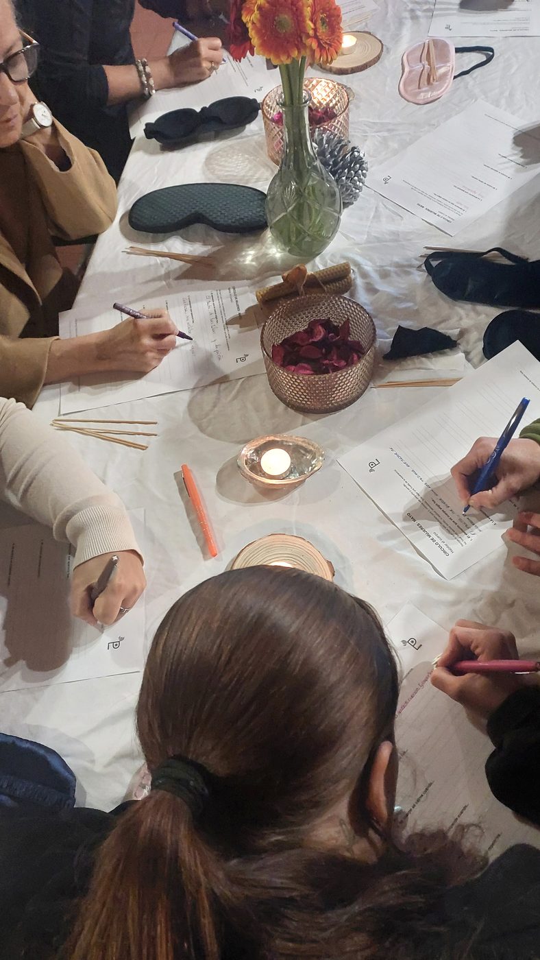 Detalle de manos escribiendo durante un círculo de mujeres.