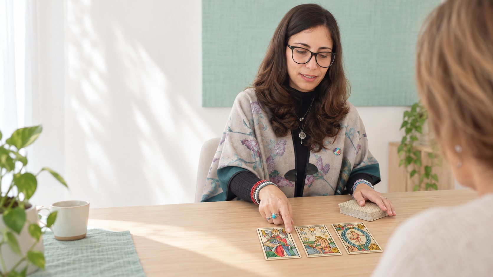 Patricia acompaña una lectura de Tarot de Marsella frente a otra mujer, en un espacio luminoso.